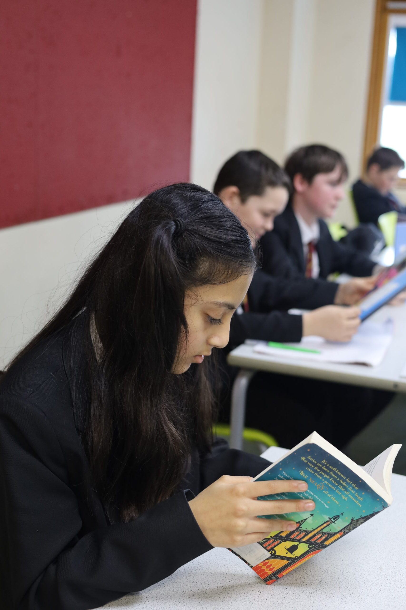 Classroom students reading books and using tablets at Kings School, Hampshire, UK.
