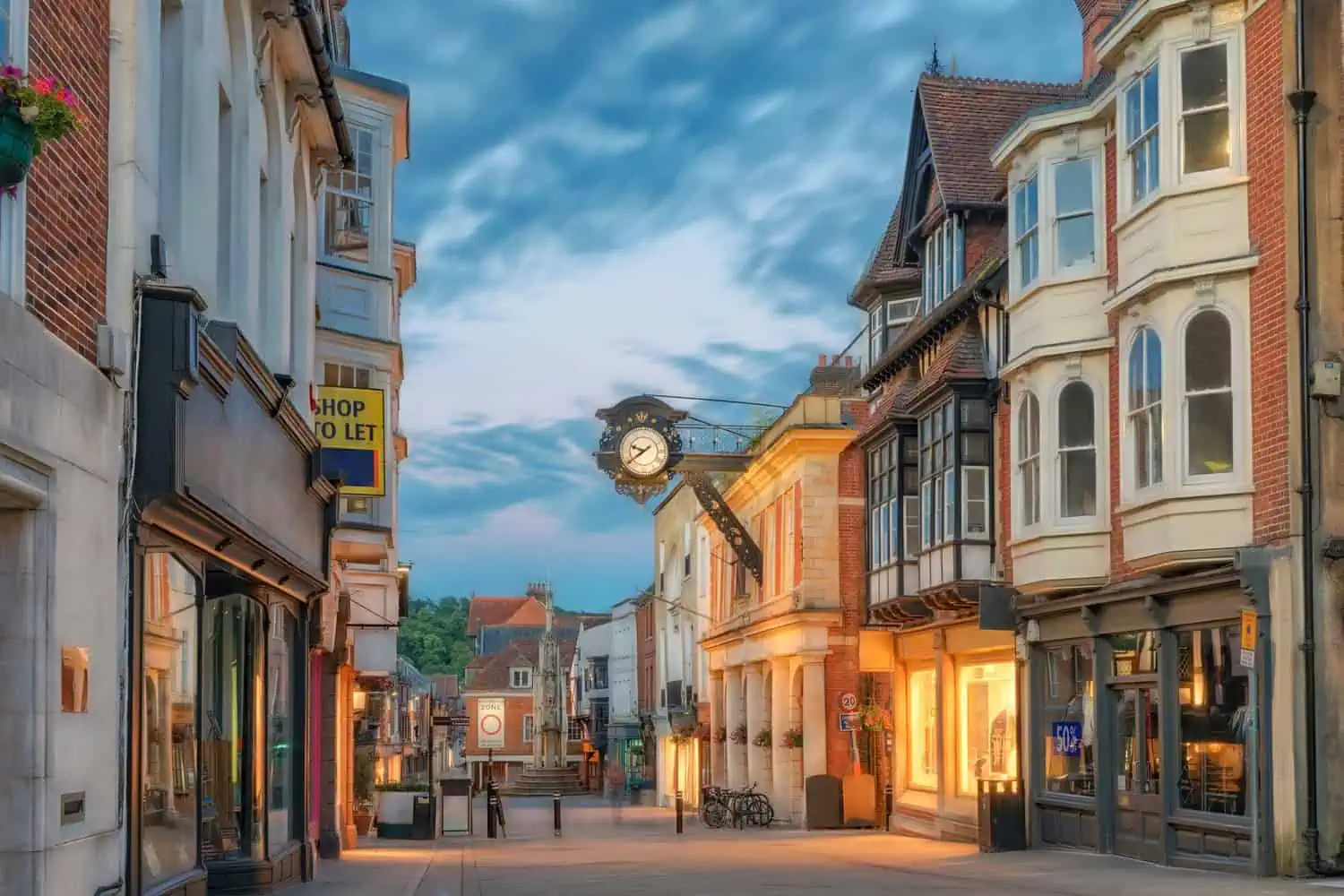 Bright town street with historic buildings, shops, and a prominent clock in Alresford, Hampshire.