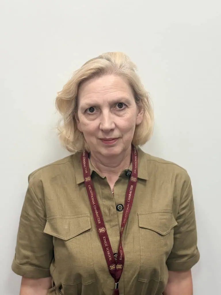 Female school governor at Kings School in front of plain wall.